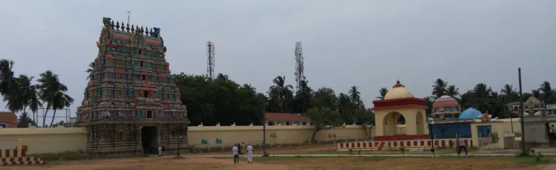 A tall carved tower beside the wall, with a yellow pavilion and a blue dome to the right