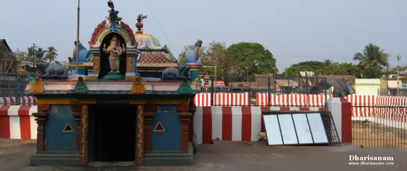 A small colourful Vinayakar shrine beside a striped tank wall