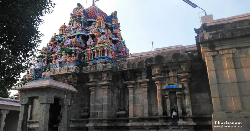A brightly painted tower with many figures rises over a plain stone wall with pilasters and a stone porch