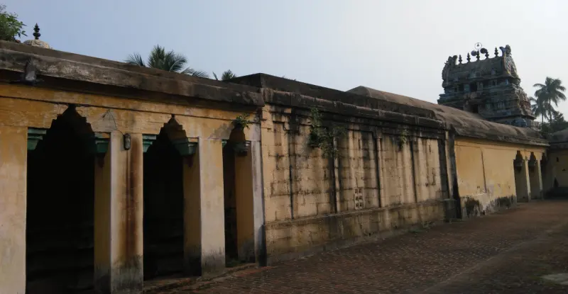 A long corridor wall with arched openings, tower behind