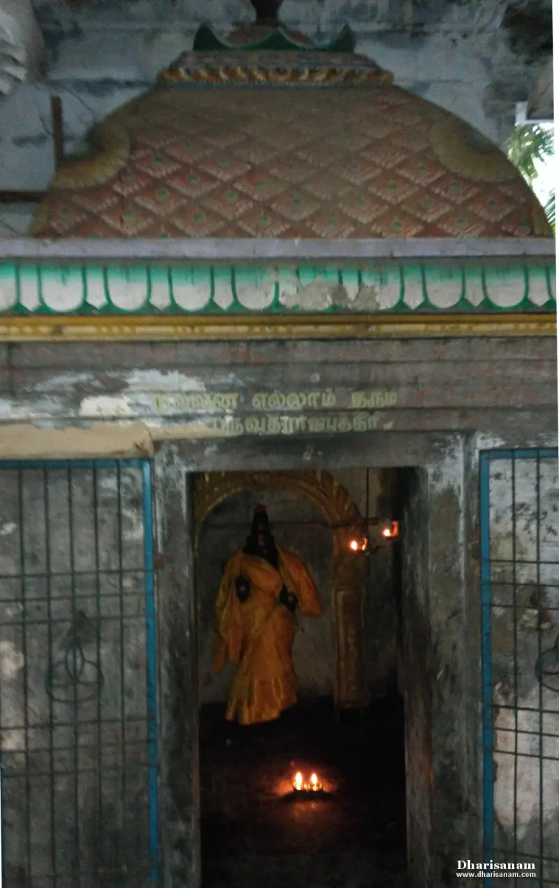 Small shrine with a patterned dome and a tamil inscription, a draped deity standing inside by two oil lamps