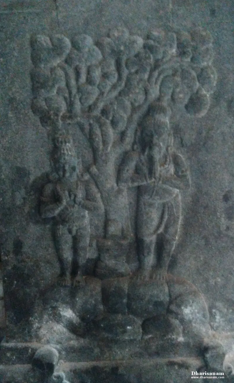 A worn stone relief of two standing figures on either side of a large leafy tree