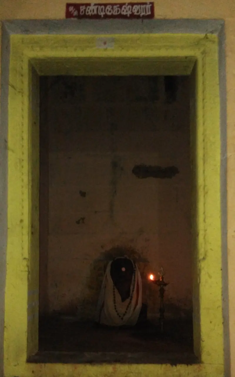 A draped idol with a lamp inside a yellow-framed shrine