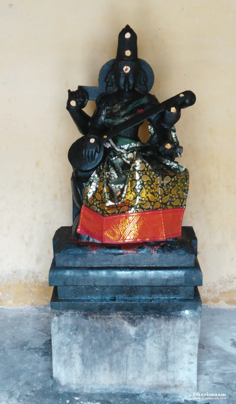 Seated black stone Saraswathi idol holding a veena, dressed in a green and red cloth