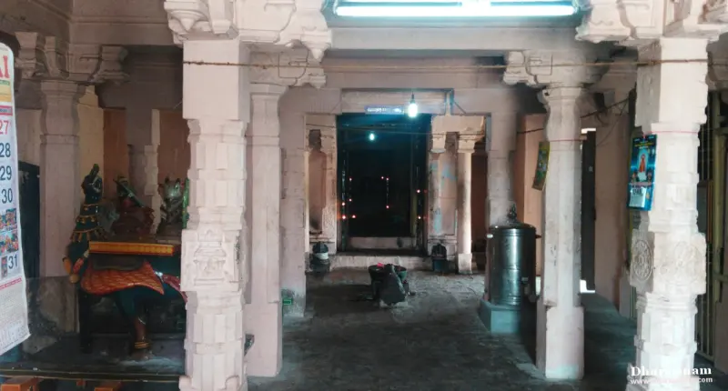 White pillared hall with idols on the left and a dark doorway at the far end