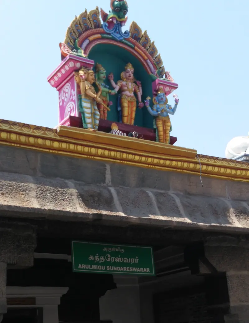 A stone doorway under a green board naming Sundareswarar, with painted figures on the roof above.