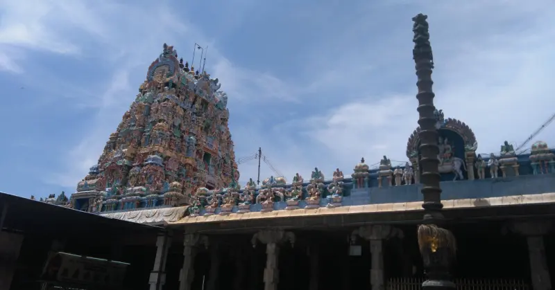 A colourful tower rising behind the hall roof, with a tall stone pillar on the right