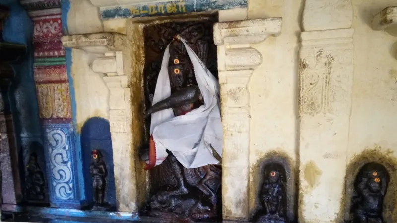 Dark stone figure draped in white cloth in a niche, with small figures in recesses beside it