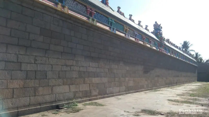 A long stone wall with a painted roof edge running into the distance beside an open path.