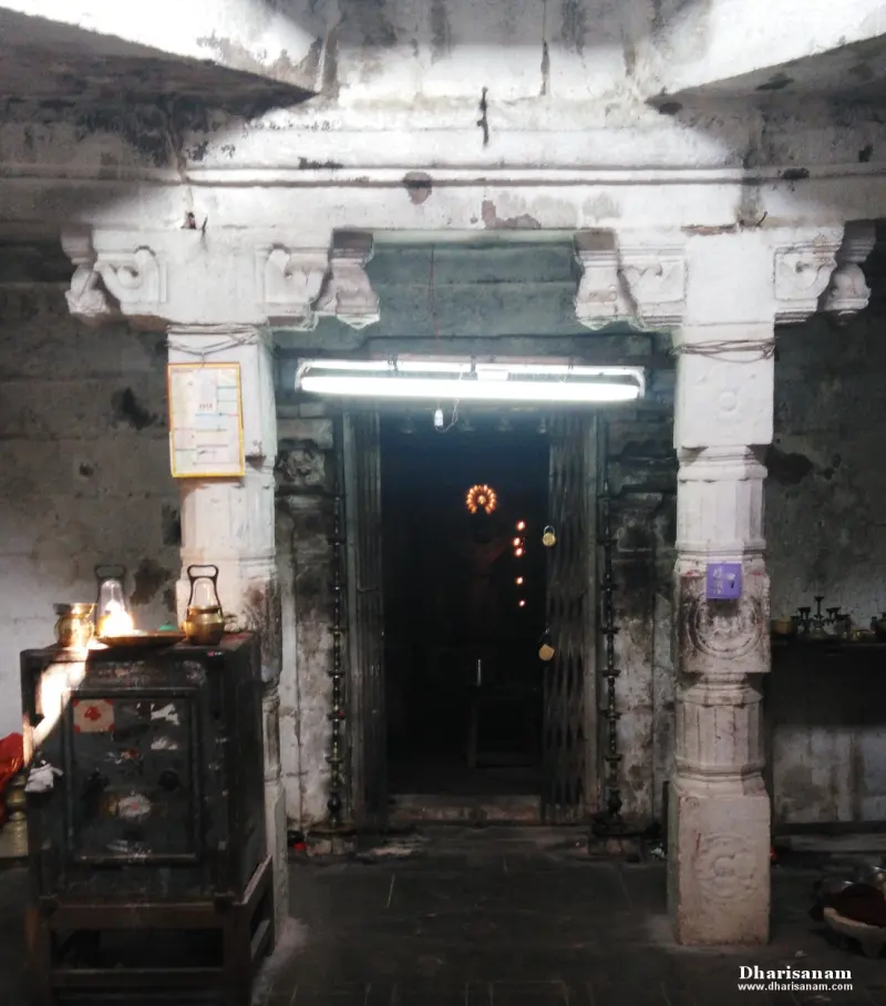 A doorway with an open grille gate and tall lamp stands, with a glowing lamp at the far end