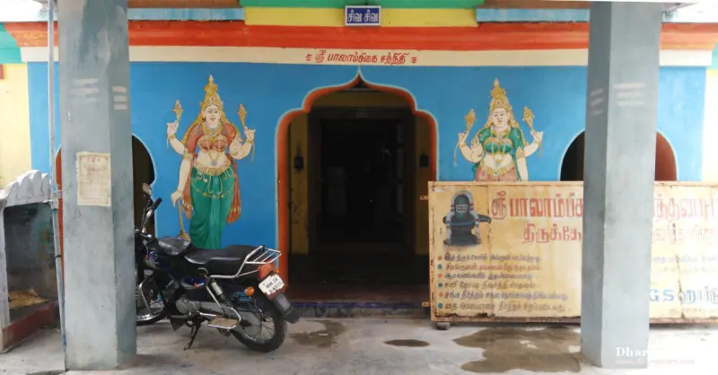 Blue shrine front with two painted goddess figures beside the doorway and a sign board on the right