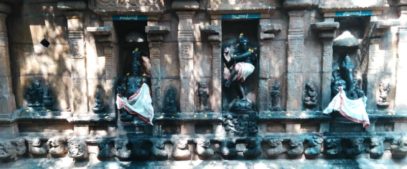 Three idols in separate wall niches, the middle one a dancing figure, above a row of small carved figures
