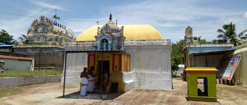 Whitewashed sanctum under a yellow dome, with a small porch where two people stand