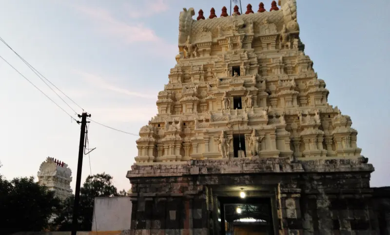 A tiered gopuram covered in sculptures above a dark stone base with an open entrance.