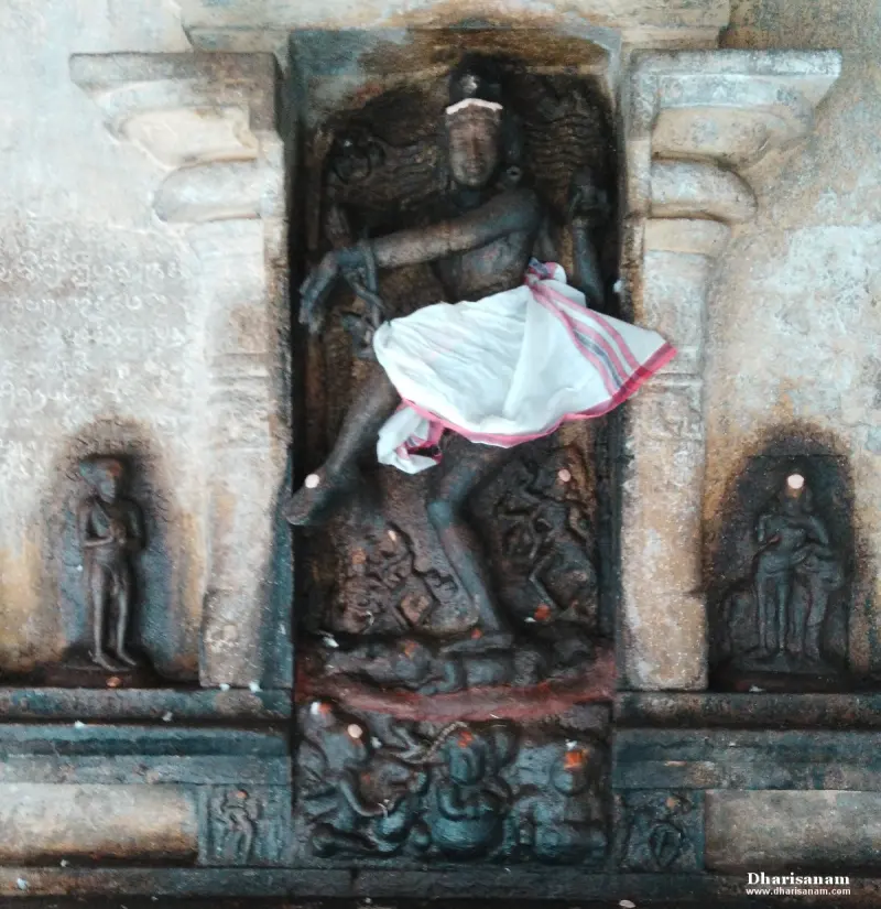 Stone figure in a dancing pose in a niche, with a white cloth across the hips