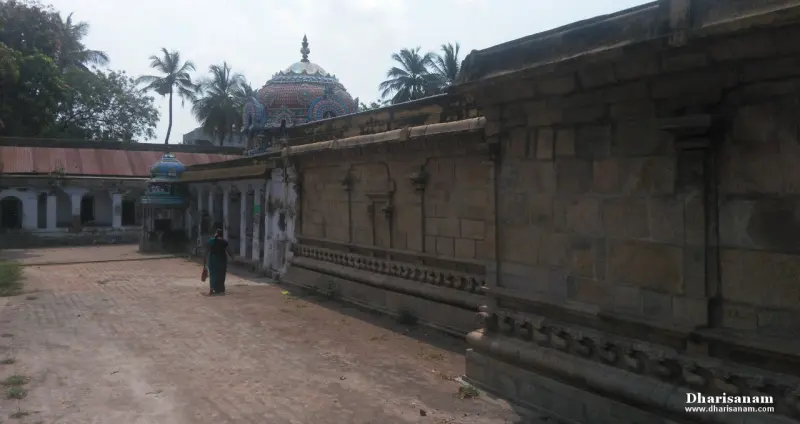 Long stone wall beside a paved path, with a domed shrine and a person walking