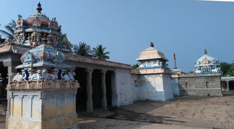 Courtyard with colourful shrine towers, a flagstaff and a pillared hall under a clear sky