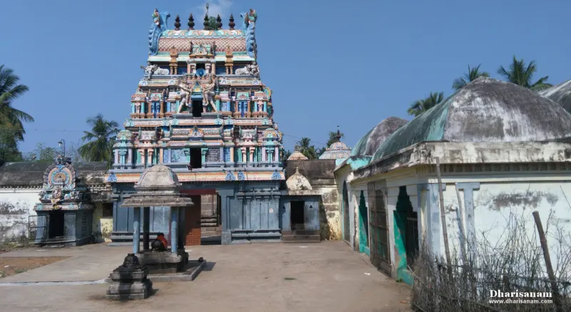 A painted gopuram above a gateway, with a small shrine in front and domed halls to the right