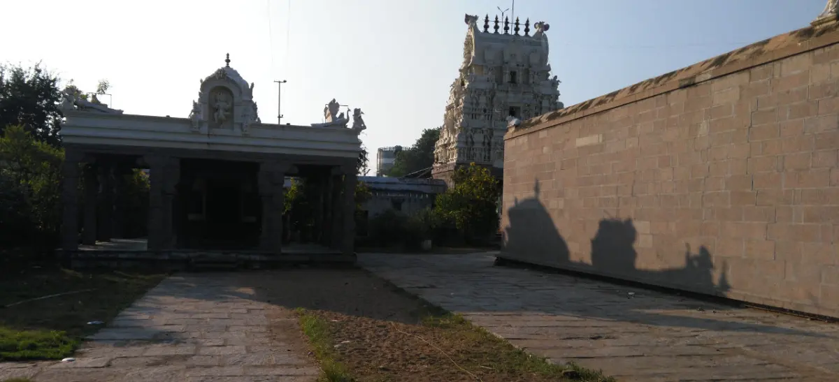 A stone hall and tall white tower behind a high temple wall