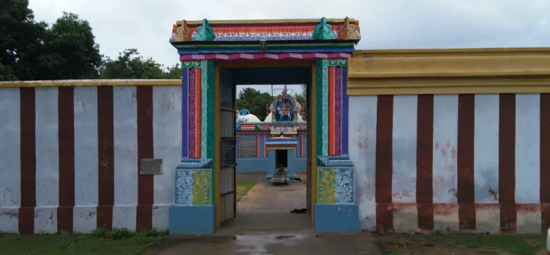 A painted entrance arch in a striped wall, with a shrine seen beyond it