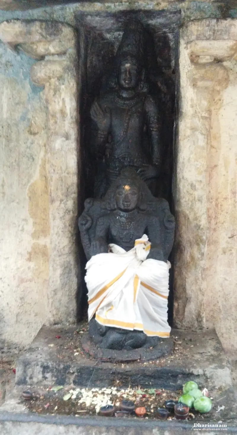 Standing stone idol behind a seated idol draped in white cloth