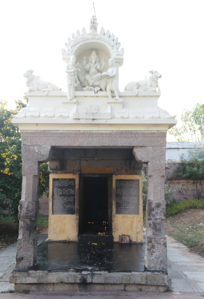 A small shrine crowned with Vinayakar, lamps lit in its dark doorway