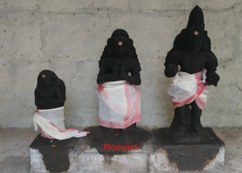 Three dark standing idols in white cloths, labelled Moovars