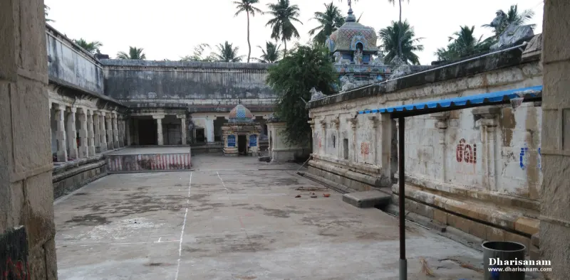 A wide paved courtyard enclosed by pillared stone corridors, with a small domed shrine at the far side