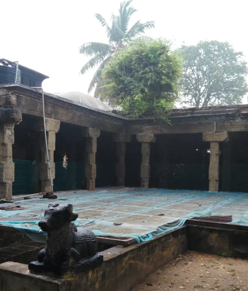 A stone Nandi in the foreground, with a pillared stone hall behind it.