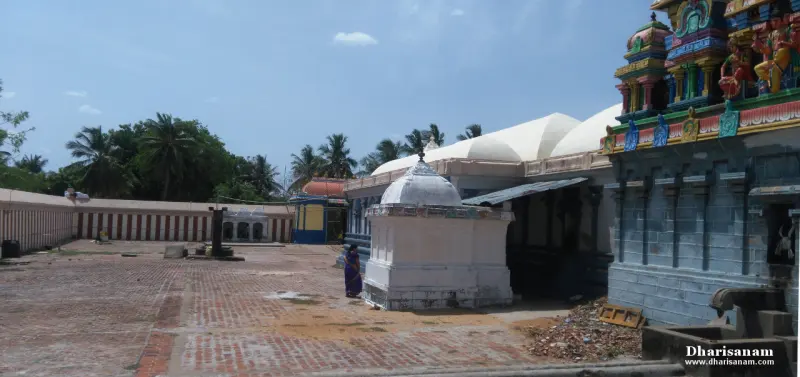 A brick-paved courtyard with a small white domed shrine, a white-roofed hall and a tower at upper right
