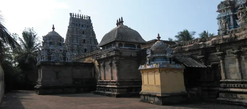 A paved courtyard with domed shrines, a small shrine in front and a tower behind