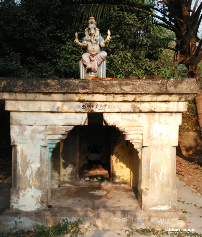 A Vinayakar statue on a small open shrine with trees behind it