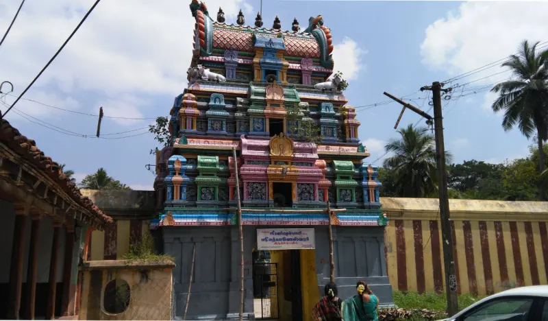 Front view of the brightly painted tiered tower above the entrance gateway, with two women walking in below