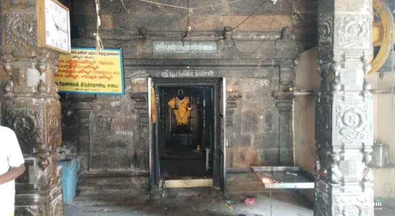 A stone doorway with name boards above it; inside, a goddess figure in a yellow garment