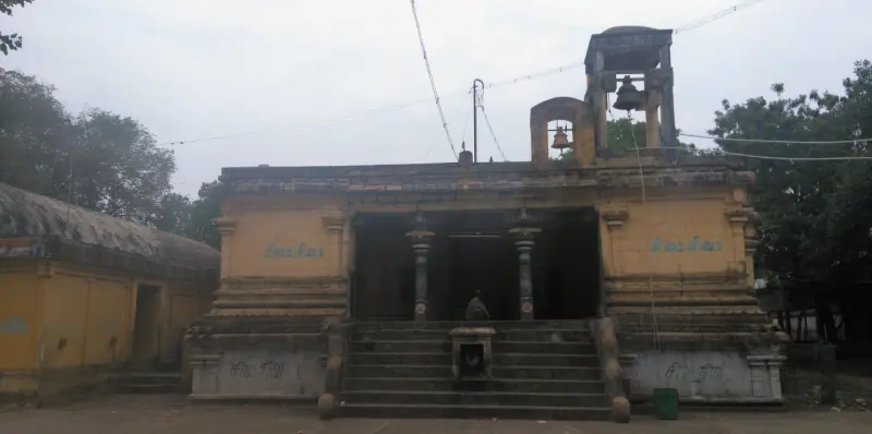 A yellow hall with steps and pillars, two bells in a tower above