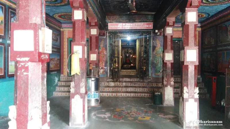 Red pillars in a hall with painted walls, and a lit shrine with an idol at the far end