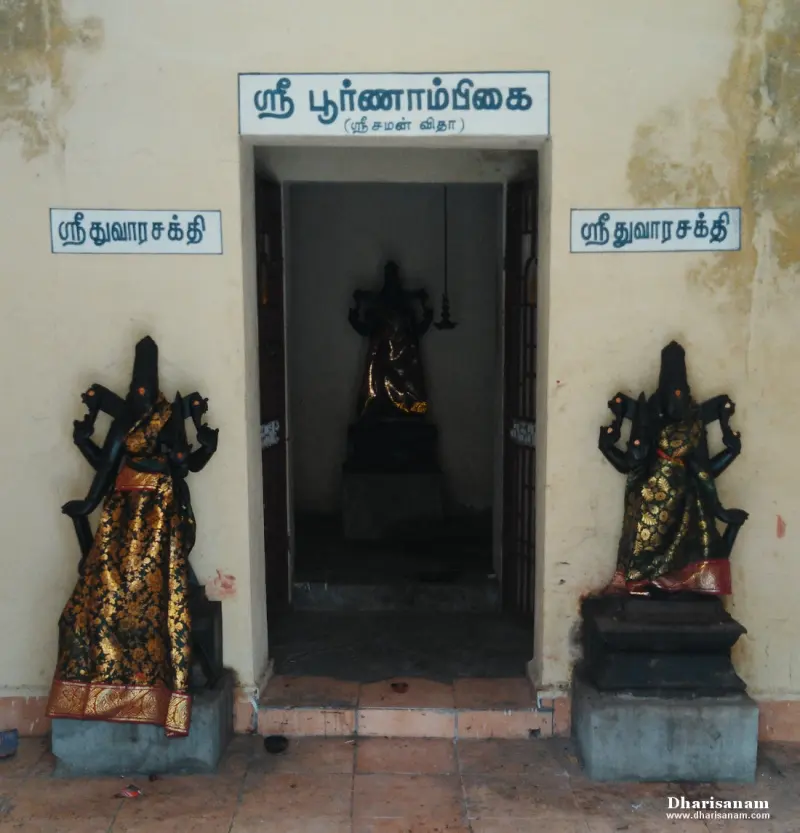 Shrine doorway under a Tamil name board, with a guardian idol on each side