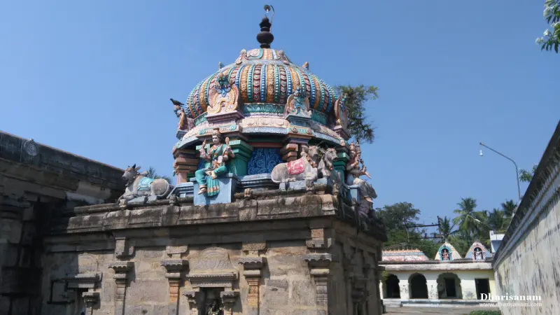 A domed shrine roof with a seated goddess figure and bull statues, above a weathered stone wall