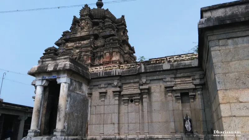 A weathered stone sanctum wall with a carved tower above and a small shrine entrance at left, under a blue sky.
