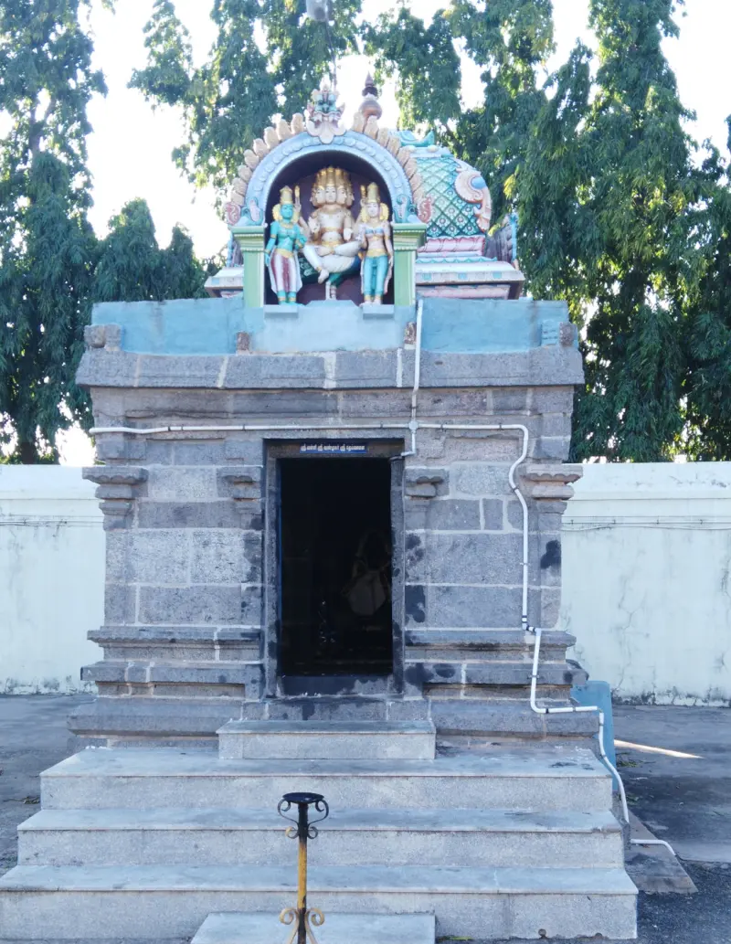 A stone shrine with three steps and a dark doorway, with a painted central figure and two attendants above