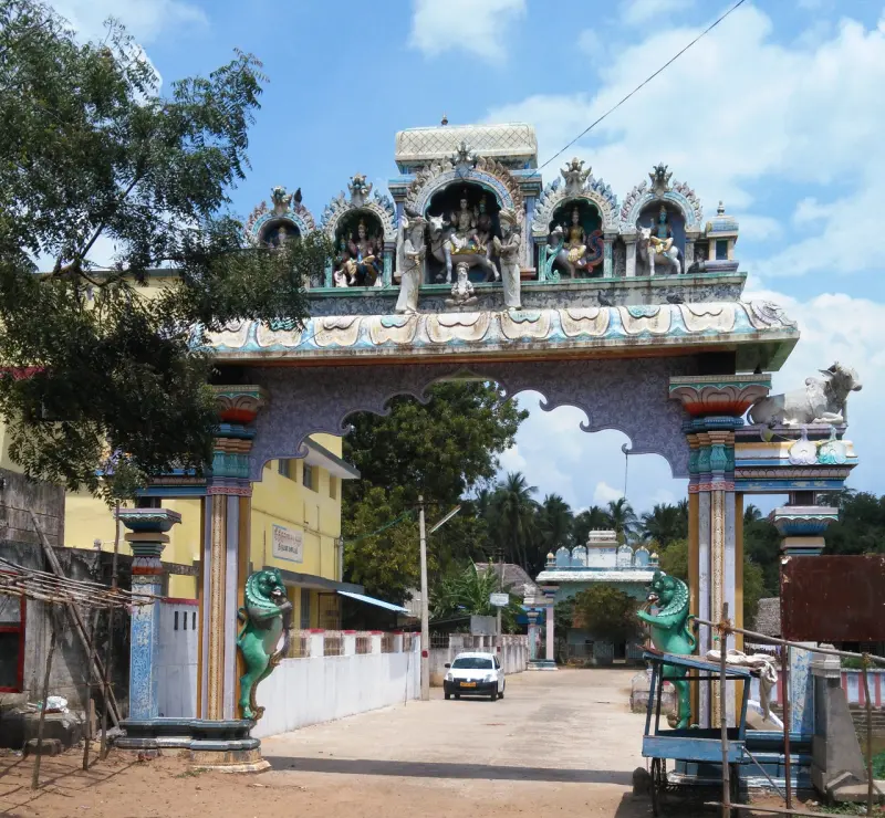 A painted arch over the road with stucco figures of deities and a bull at its corner