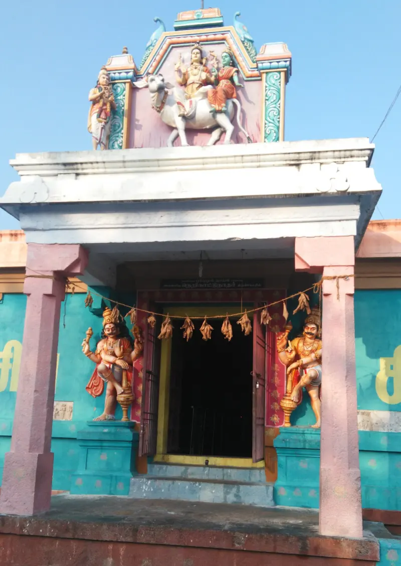 Two painted guardians at a turquoise doorway, Shiva-Parvati above