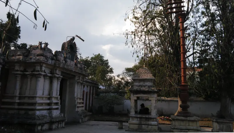 Courtyard with a tall flagstaff, a small stone shrine and a pillared hall on the left
