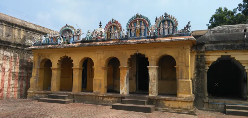 Yellow arcade building with deity figures on the roof