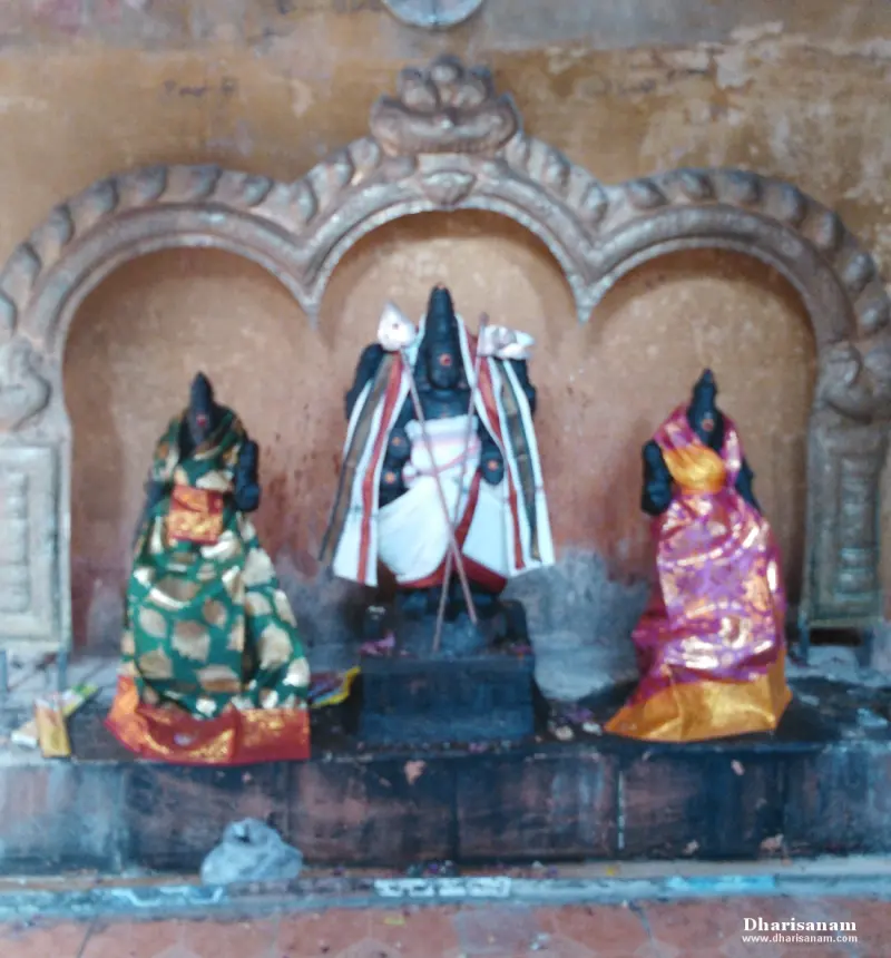 Dark stone idols draped in sarees under a carved arch
