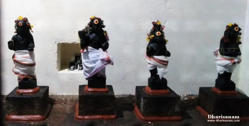Four small dark images in white cloth with flower garlands, standing on black pedestals