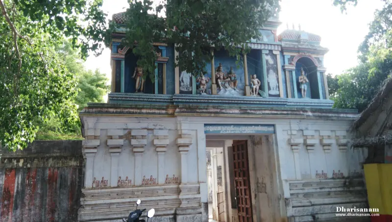 A whitewashed gateway with a wooden door and painted figures above, a scooter parked in front