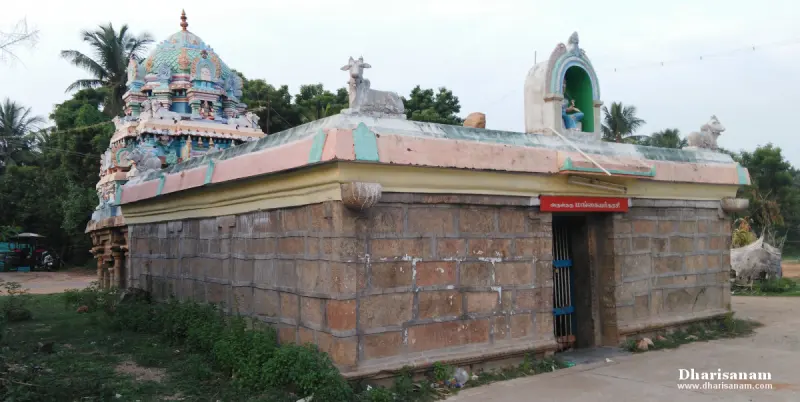 A small stone shrine with a colourful roof and a Nandhi figure, a painted tower rising behind it.