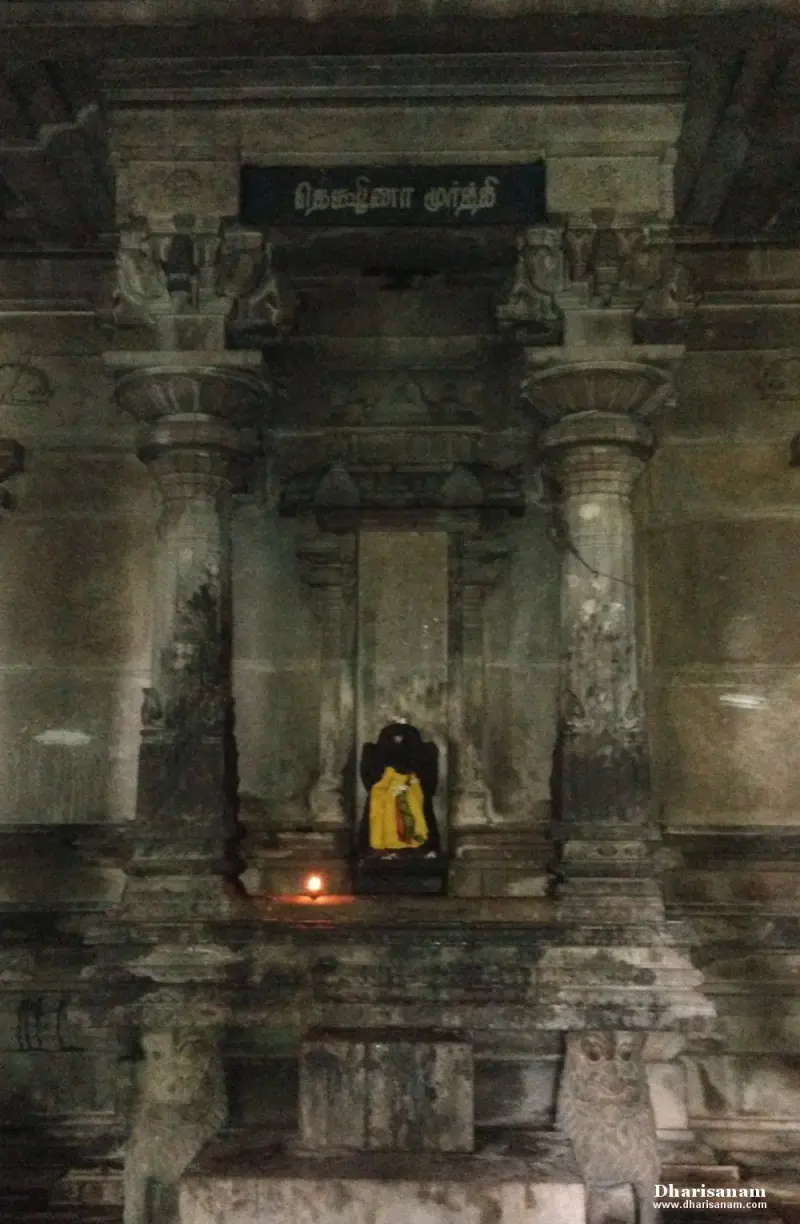 Small draped idol in a stone niche under a Tamil name board, a lamp lit