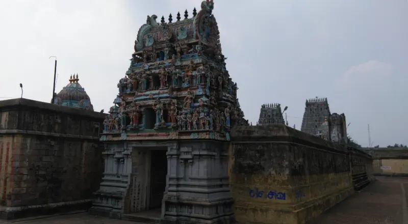 Small gopuram over a stone doorway by a high wall